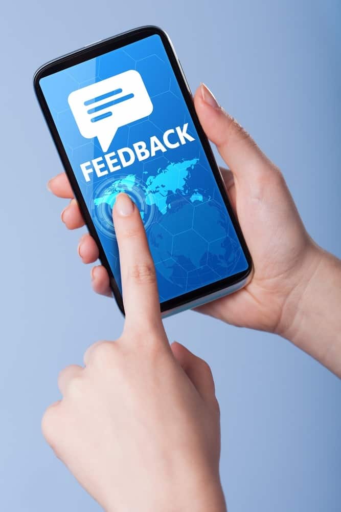 Man presses a touch screen smart phone with the symbol of feedb