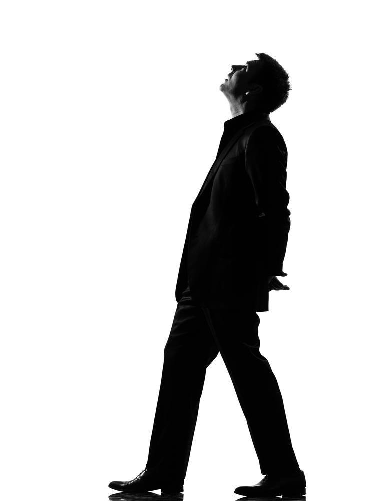 Silhouette man walking musing looking up